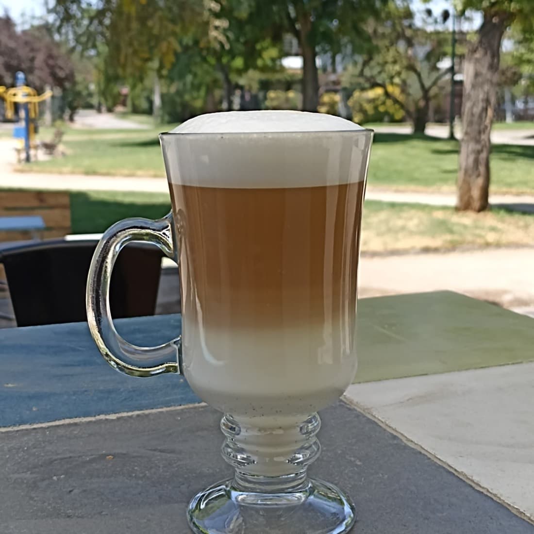 Café latte en vaso alto, con la plaza de fondo